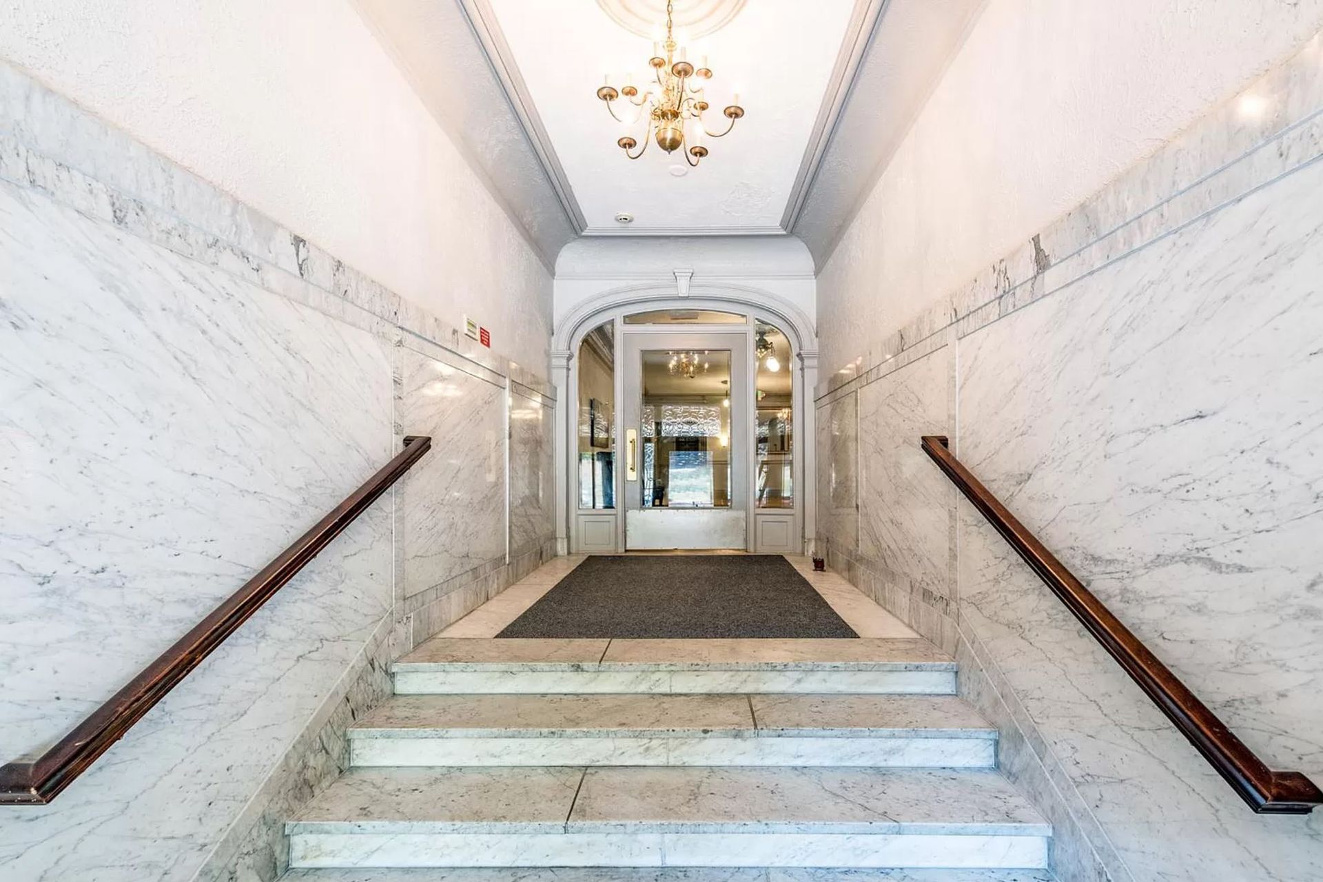 A marble hallway with stairs leading up to a doorway
