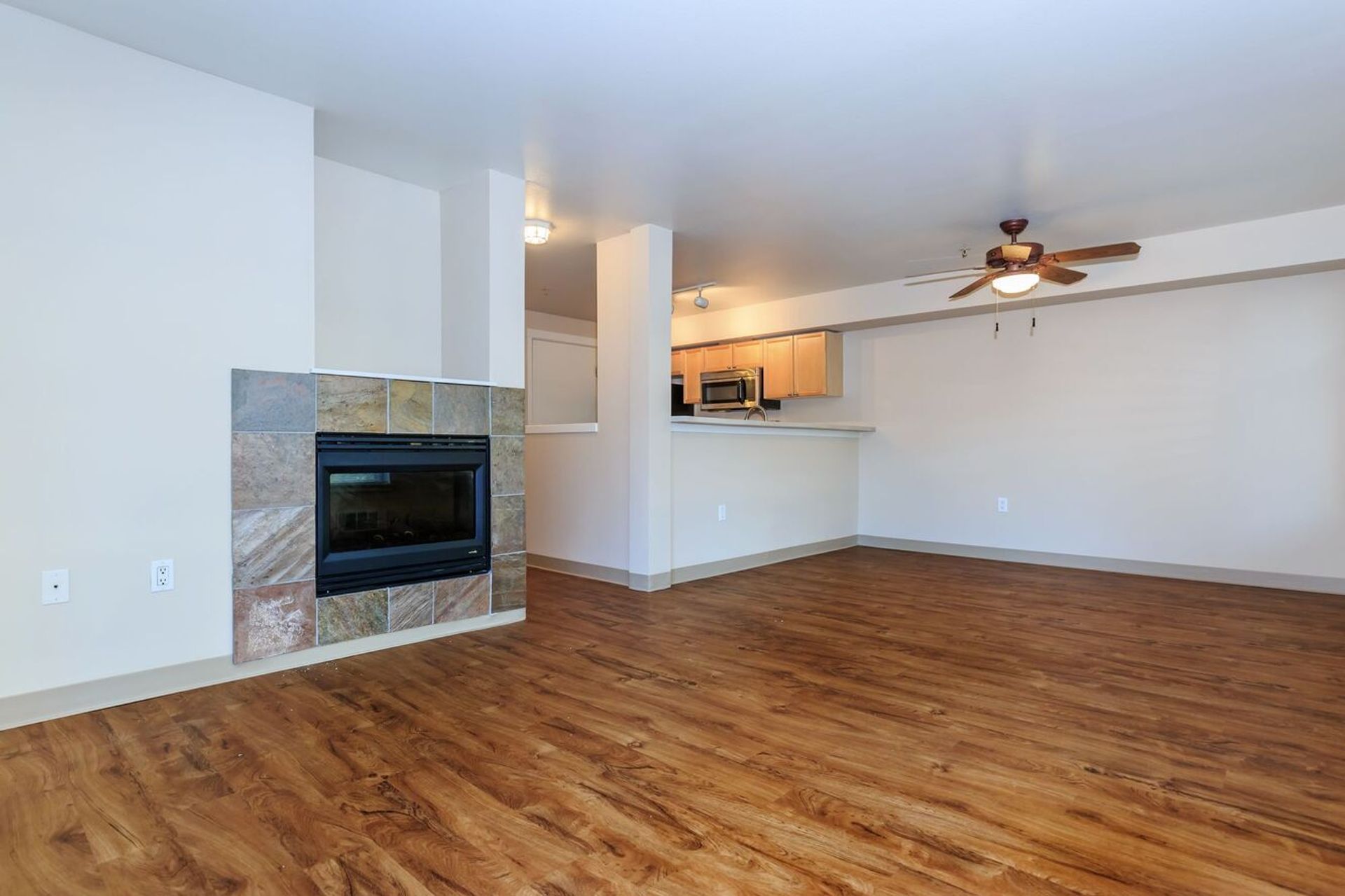 An empty living room with hardwood floors and a fireplace.