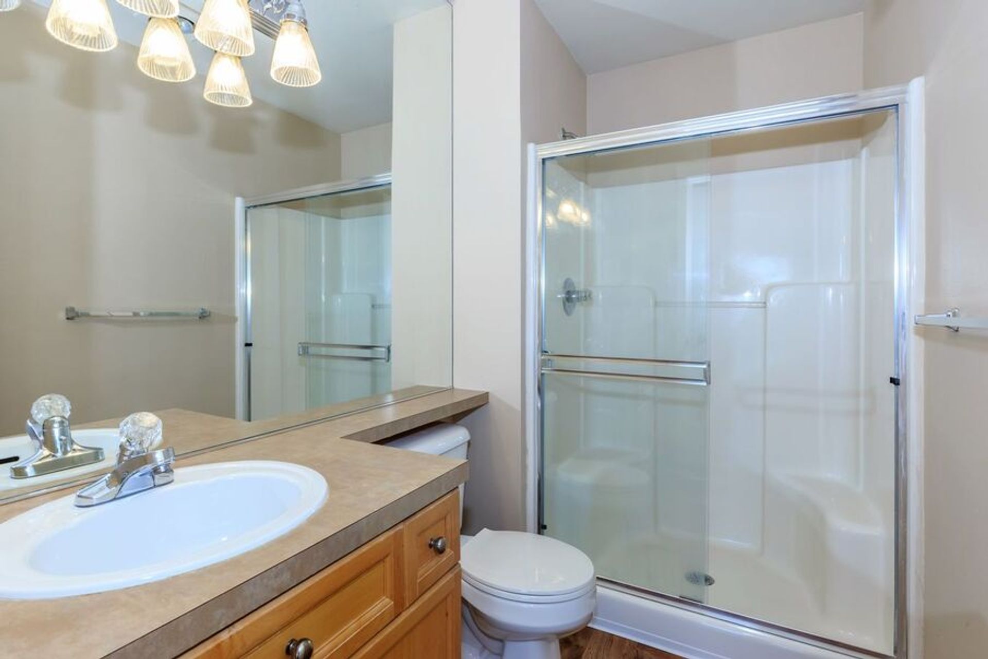 A bathroom with a sink , toilet , shower and mirror.