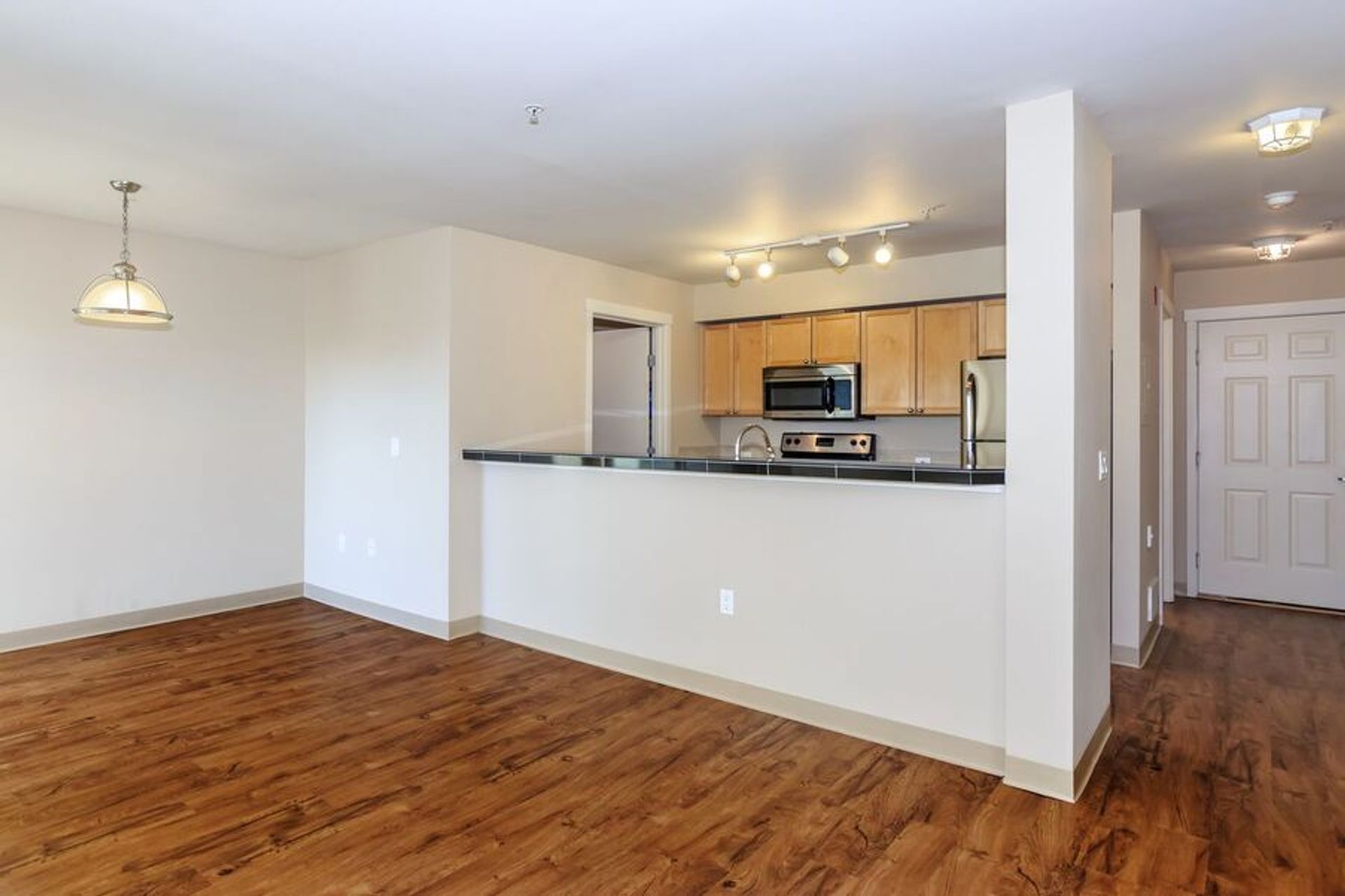 An empty apartment with hardwood floors and a kitchen.