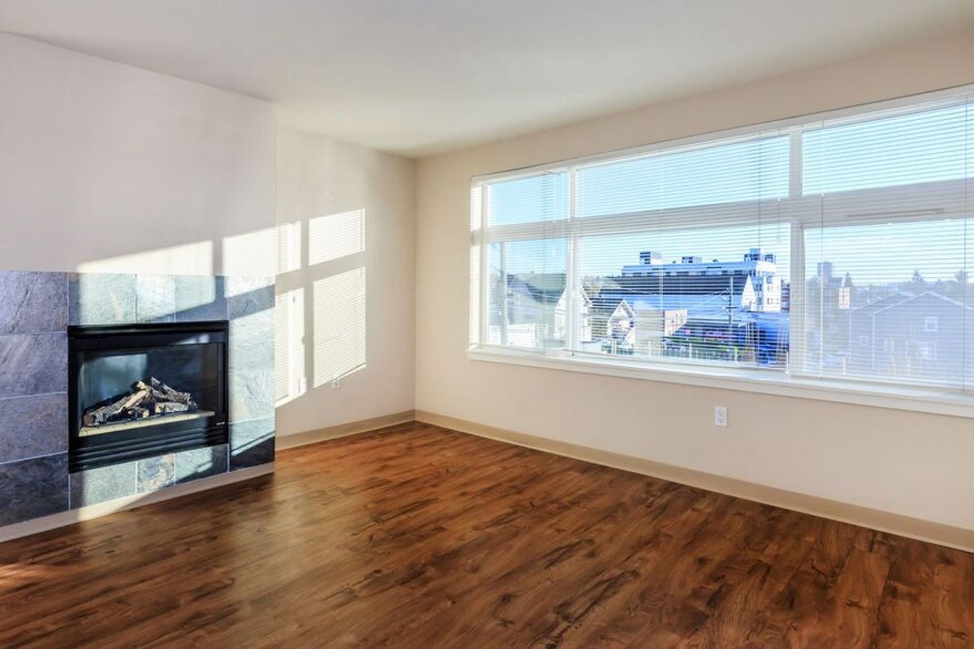 An empty living room with hardwood floors and a fireplace.