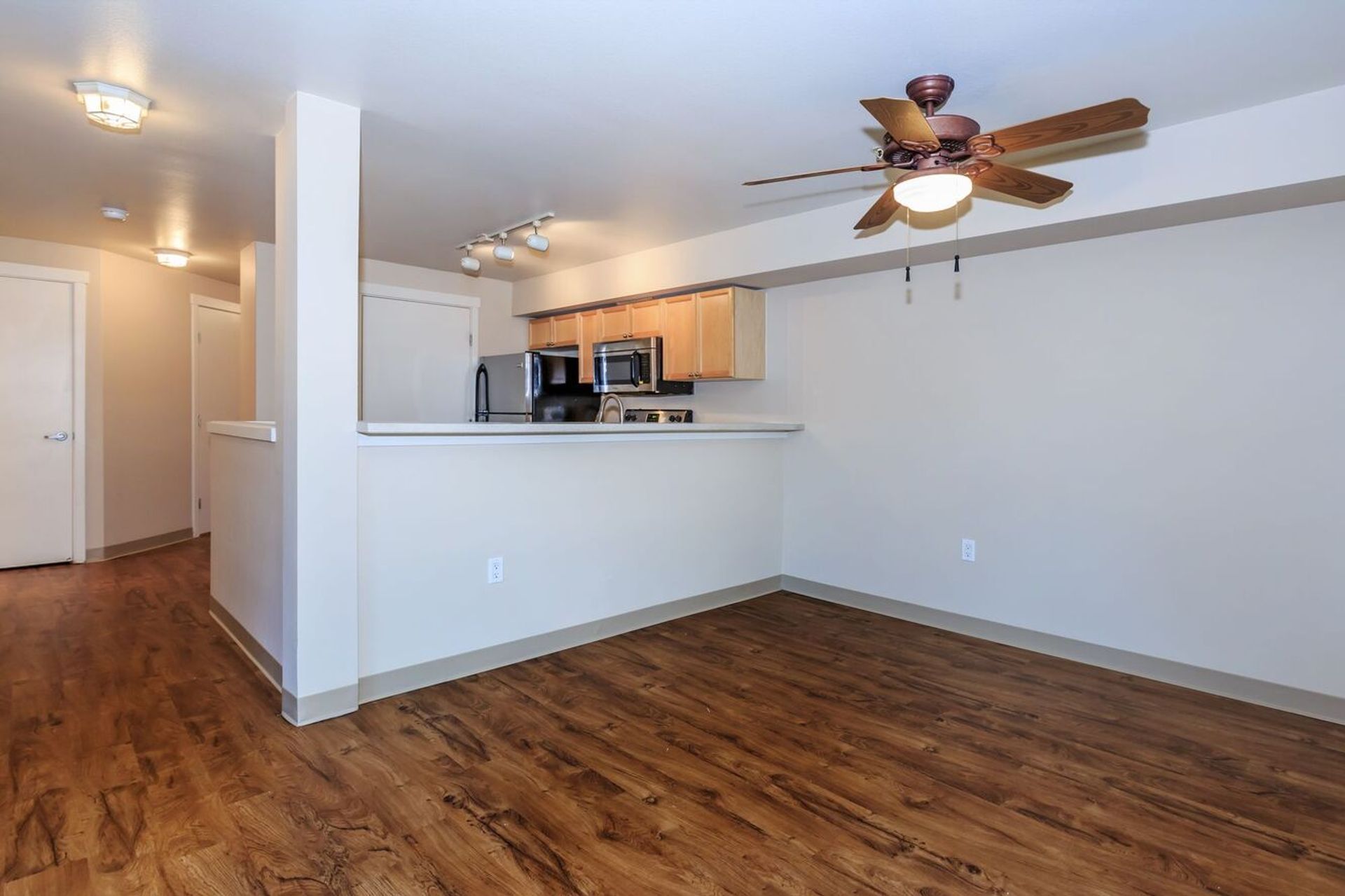 A living room with hardwood floors and a ceiling fan.