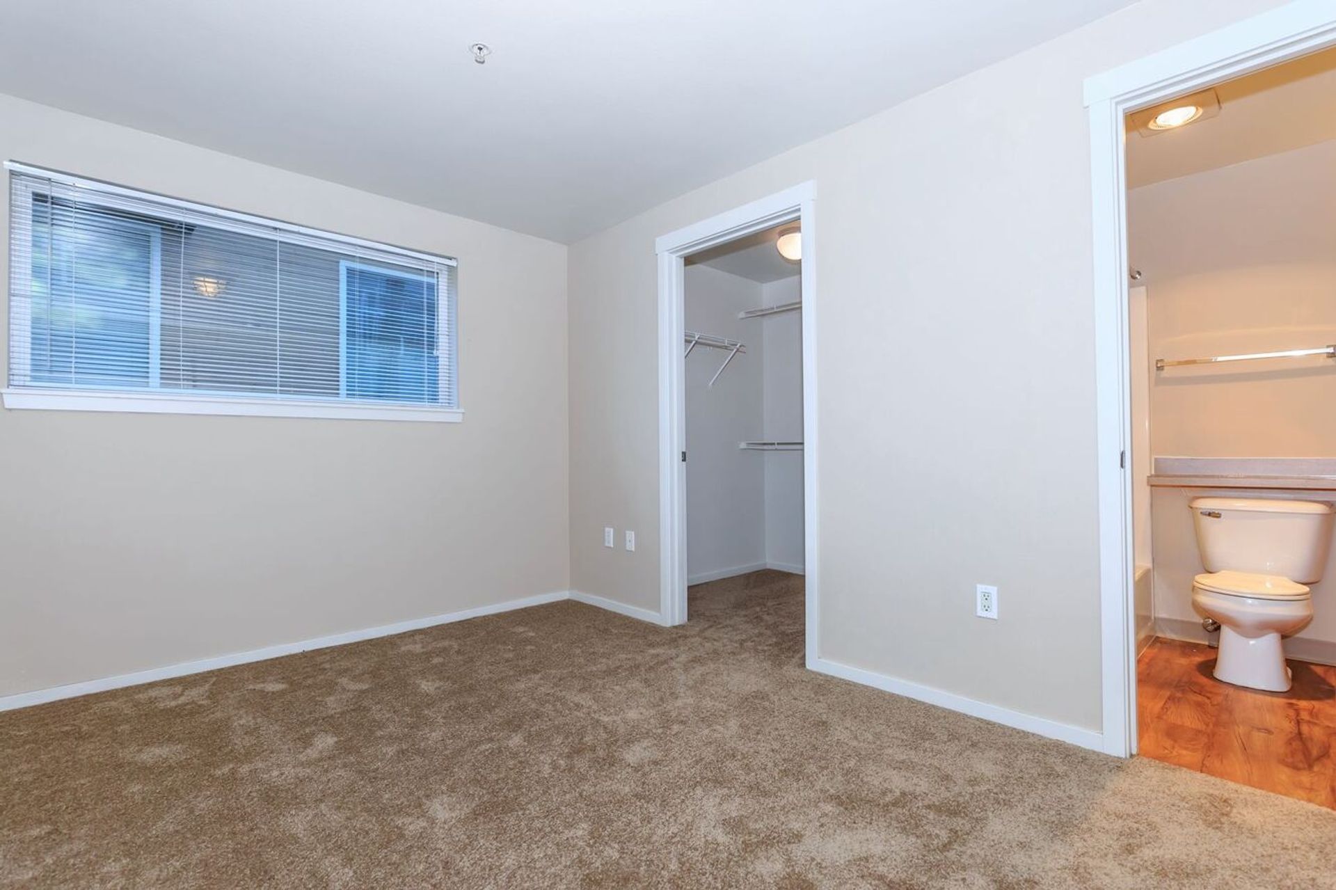 An empty bedroom with a toilet and a window.