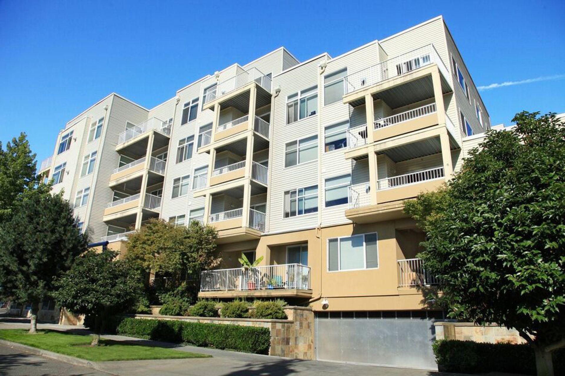 A large apartment building with lots of balconies and trees in front of it.