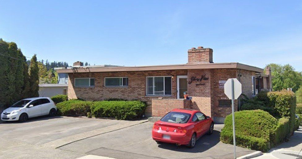 A red car is parked in front of a brick building.