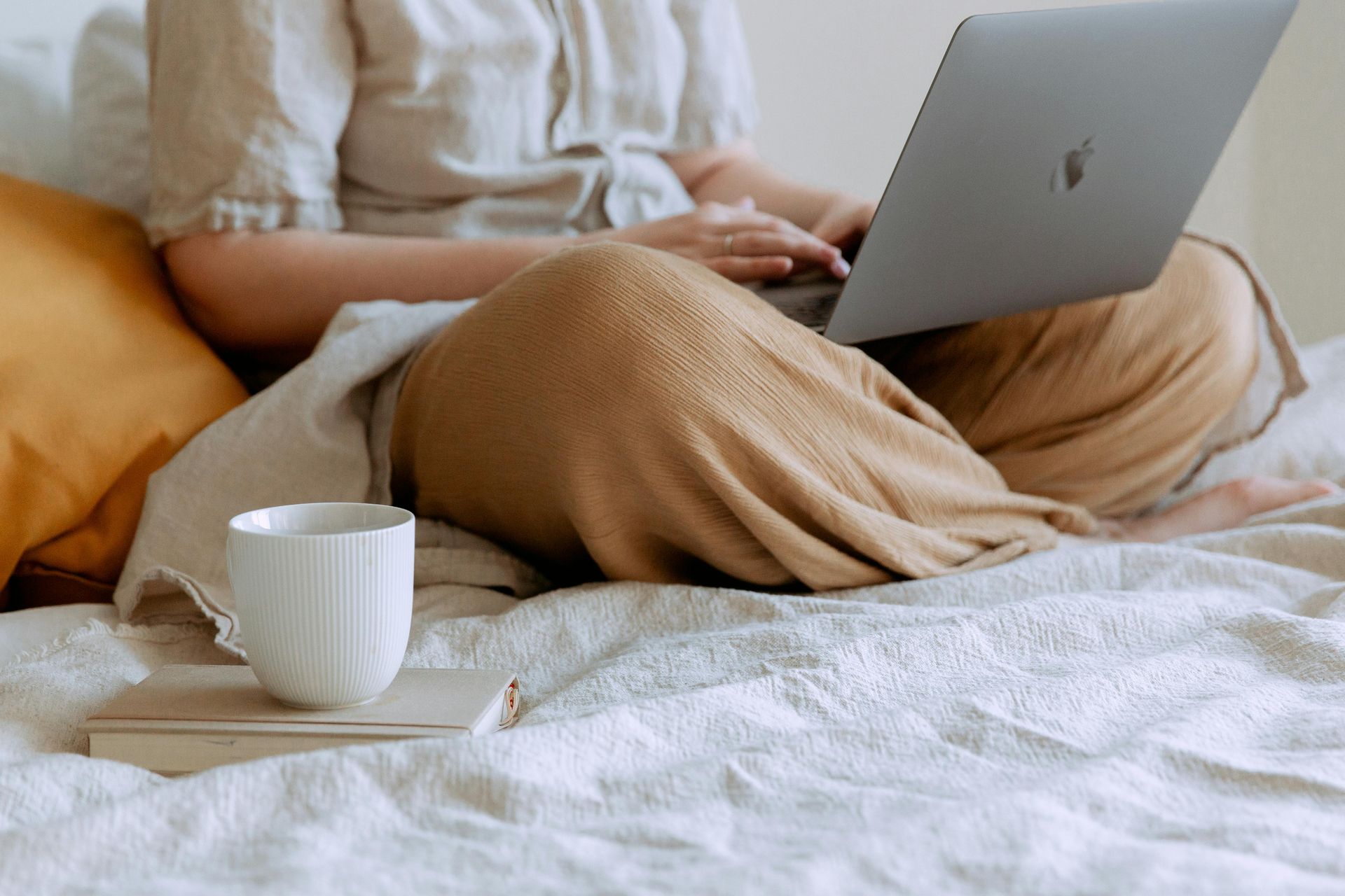 A woman is sitting on a bed using a laptop computer.