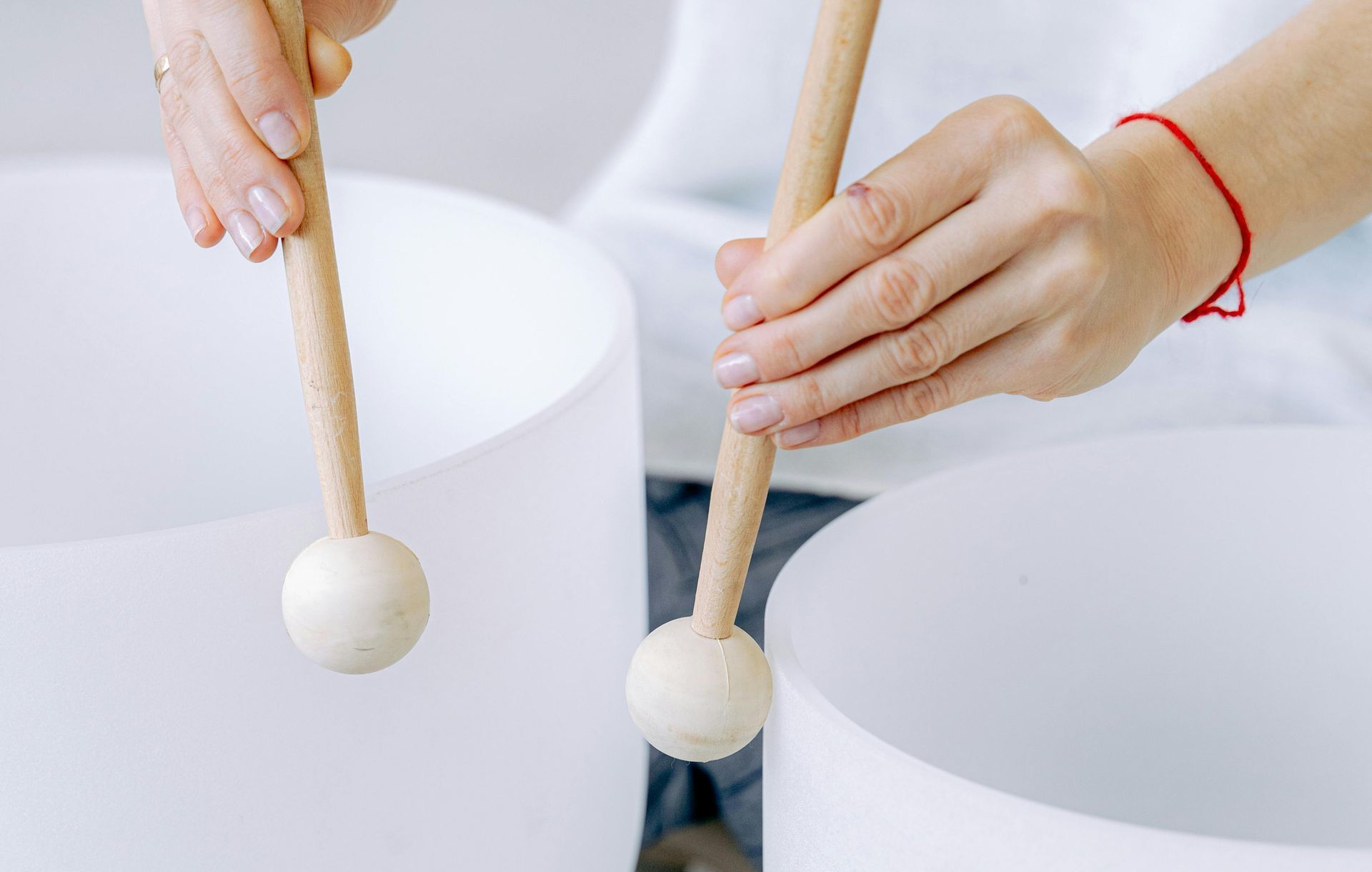 A woman is holding two wooden mallets over two white bowls.