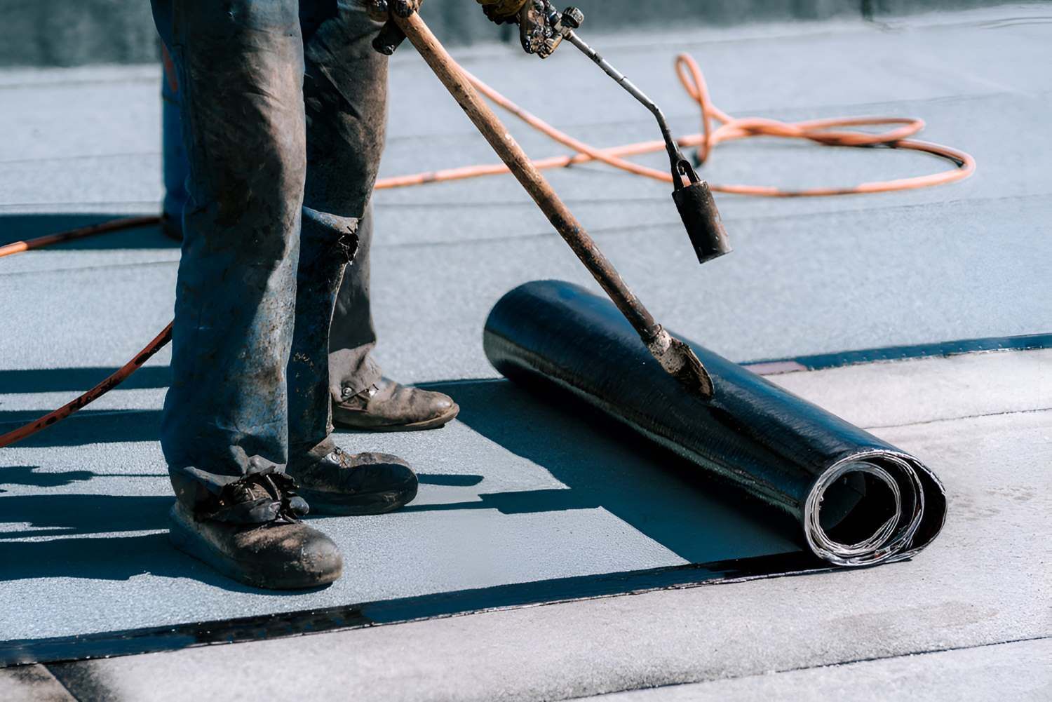 A Man Is Laying A Roll Of Sheet Membrane Waterproofing — Bananacoast Waterproofing in Korora, NSW