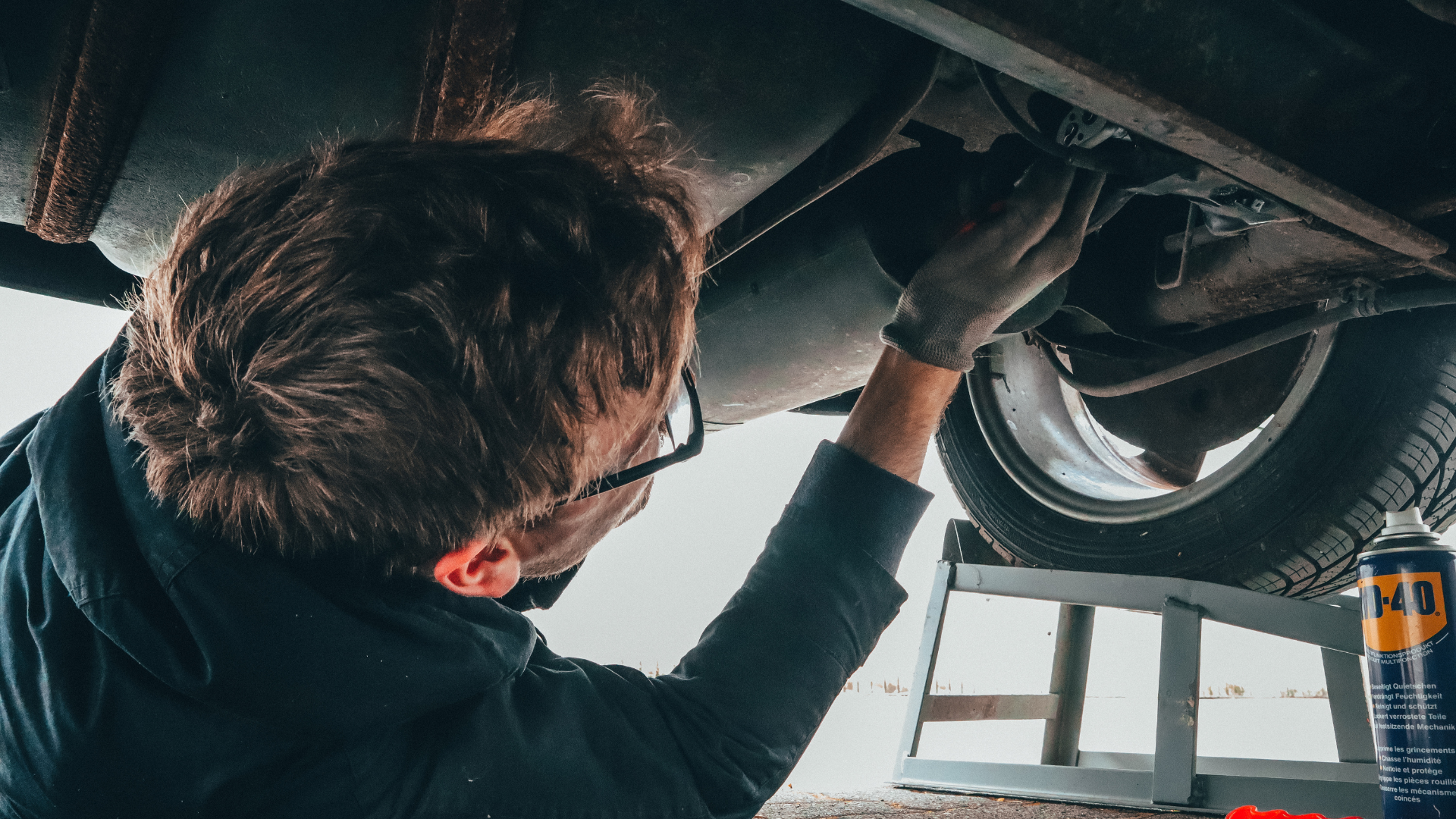 A man is working on the underside of a car.