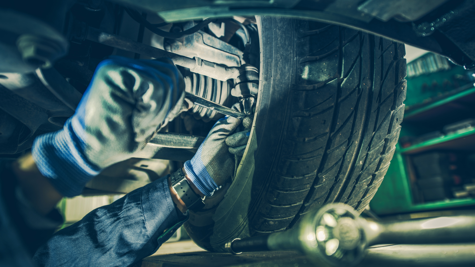A mechanic is working on the underside of a car in a garage.