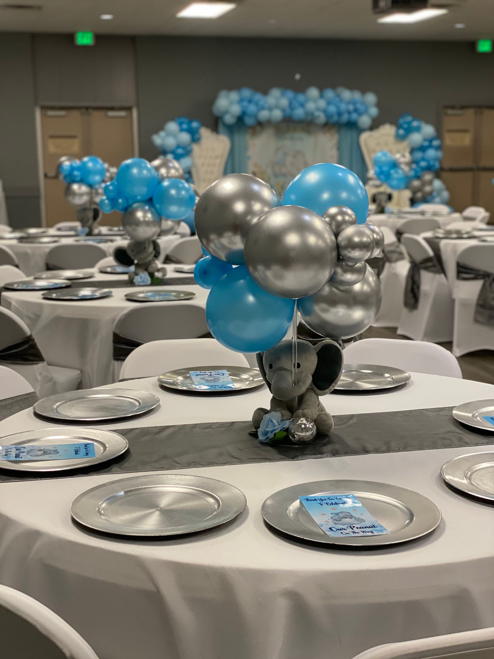A room filled with tables and chairs decorated for a baby shower.