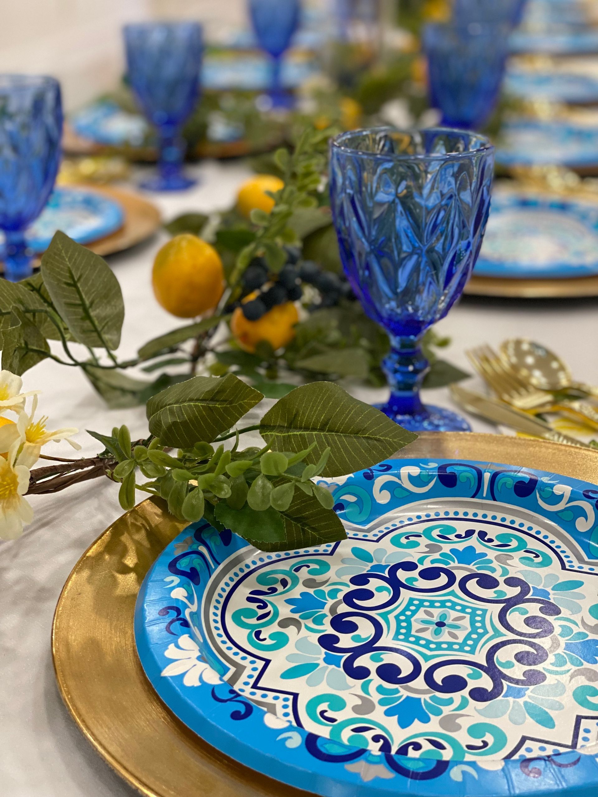 A table setting with blue plates , blue wine glasses , and lemons.
