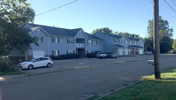 A row of houses with cars parked in front of them on a sunny day.
