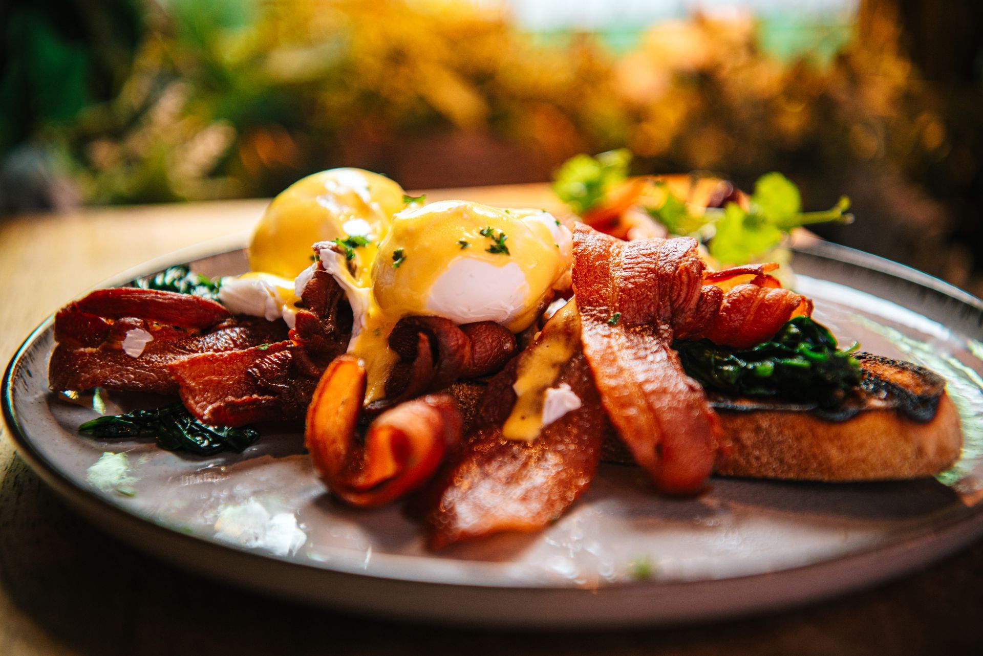 Eggs Benedict with bacon and spinach on a plate.