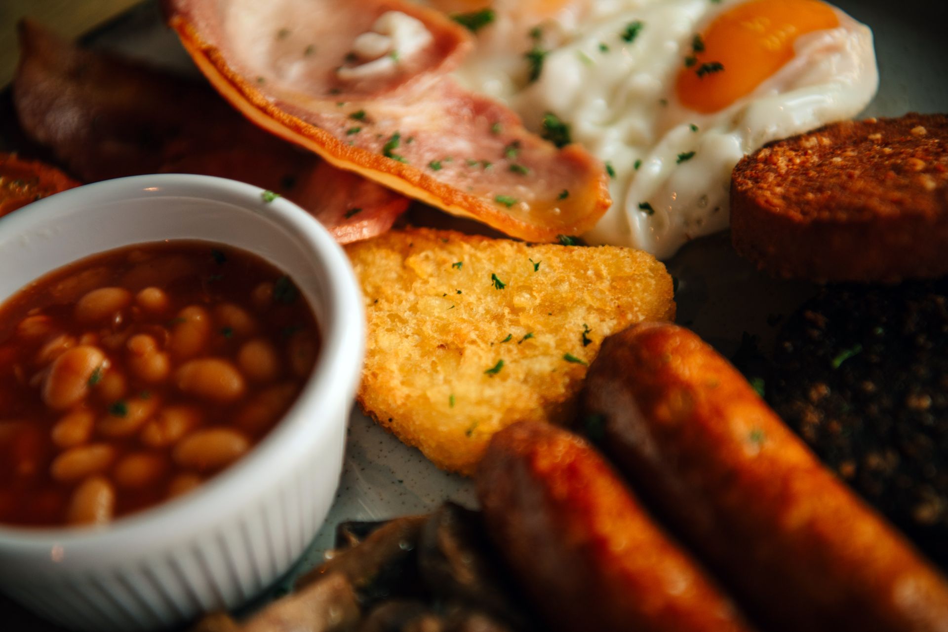 Full plate breakfast with baked beans, eggs, bacon, sausage, and hash brown.