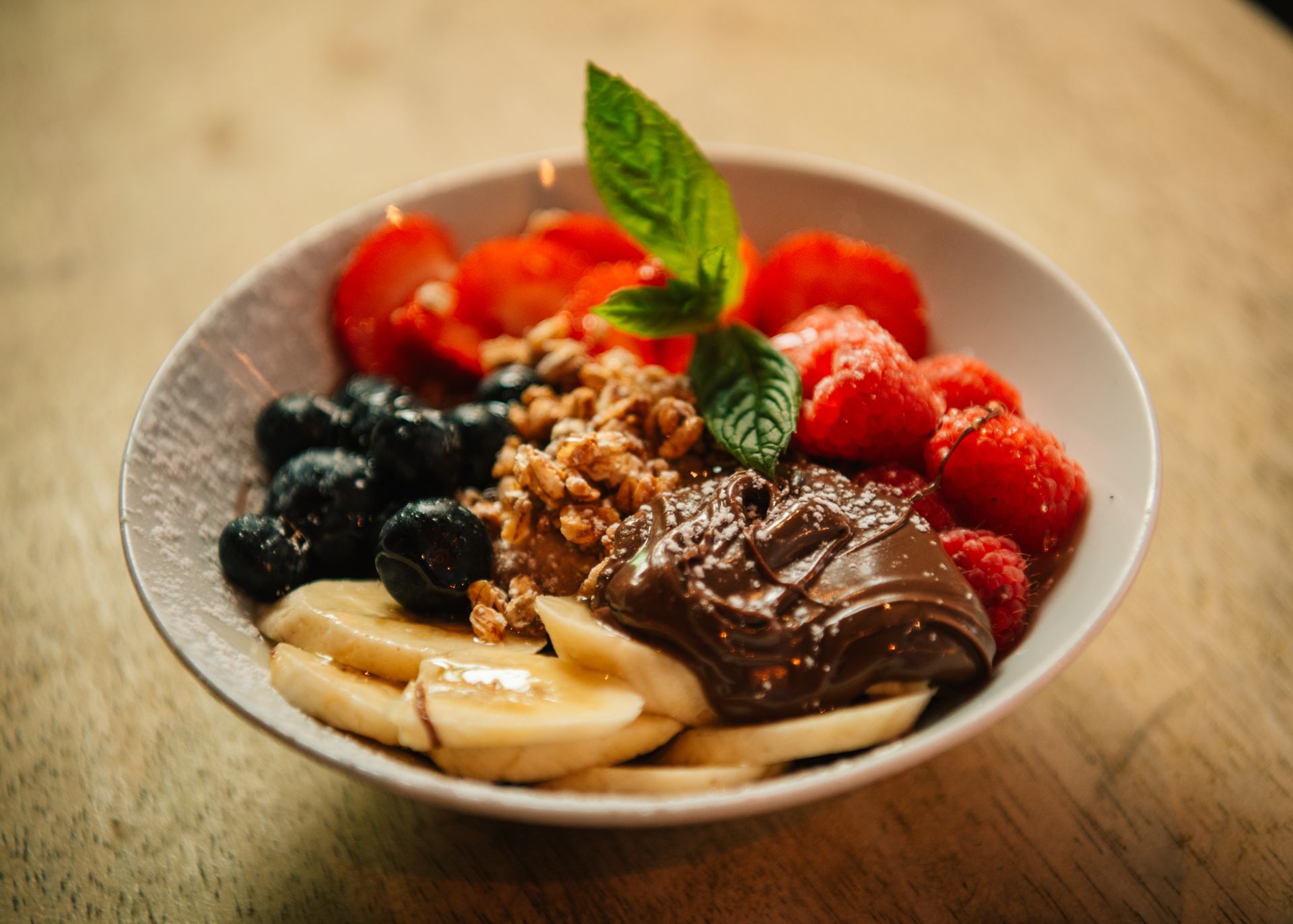 Bowl of fresh fruit, including strawberries, blueberries, raspberries, and banana slices.