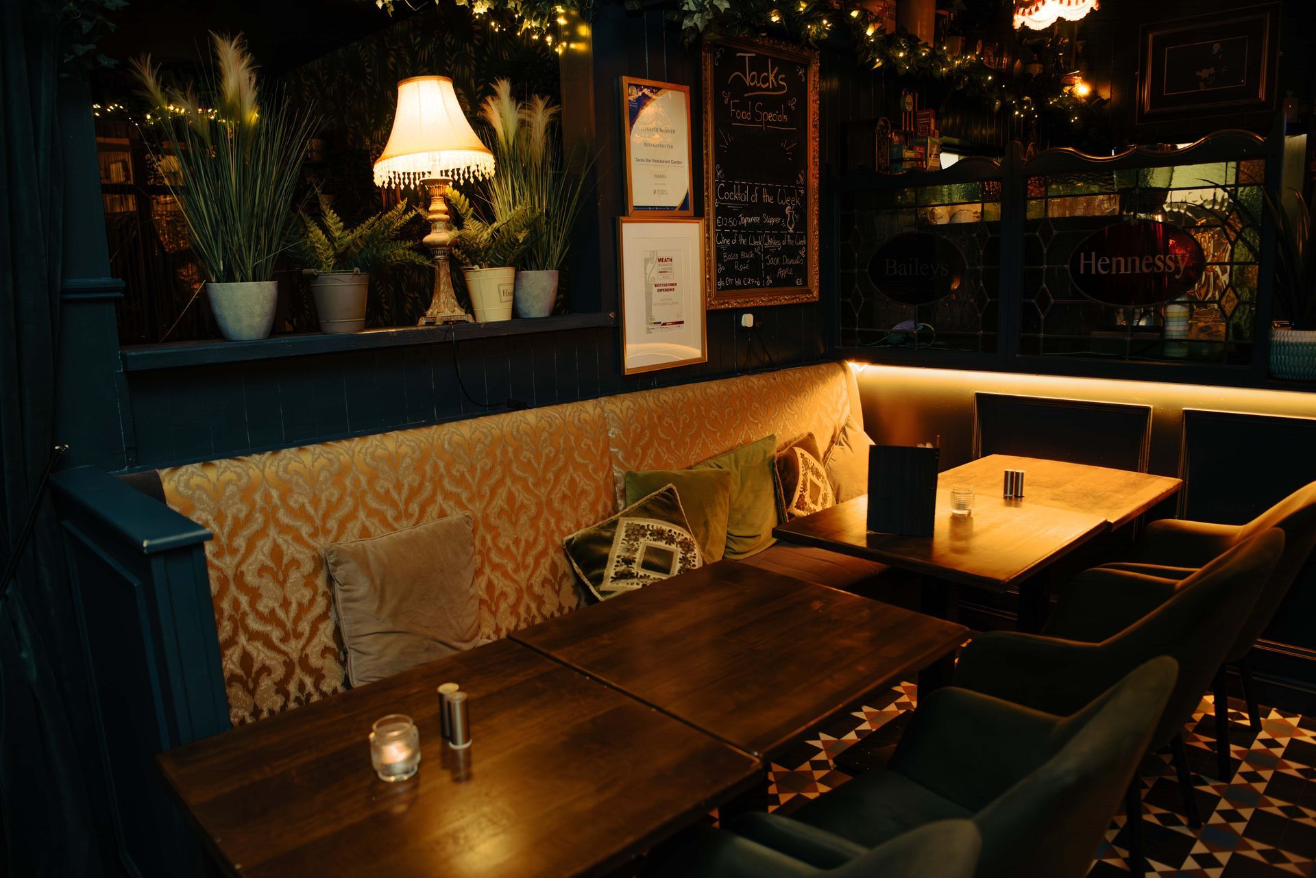 Cozy restaurant booth with dark wood tables, ornate patterned upholstery, and soft lighting.