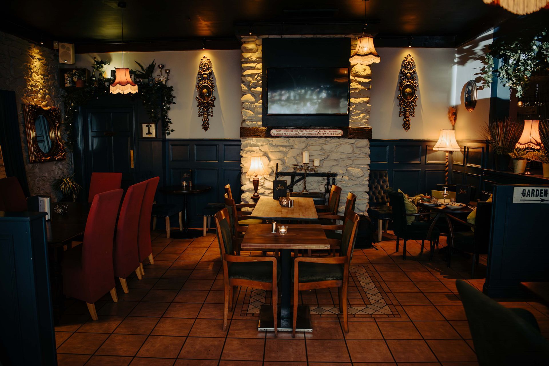 Cozy restaurant interior with dark paneling, stone fireplace, and tables set for dining.