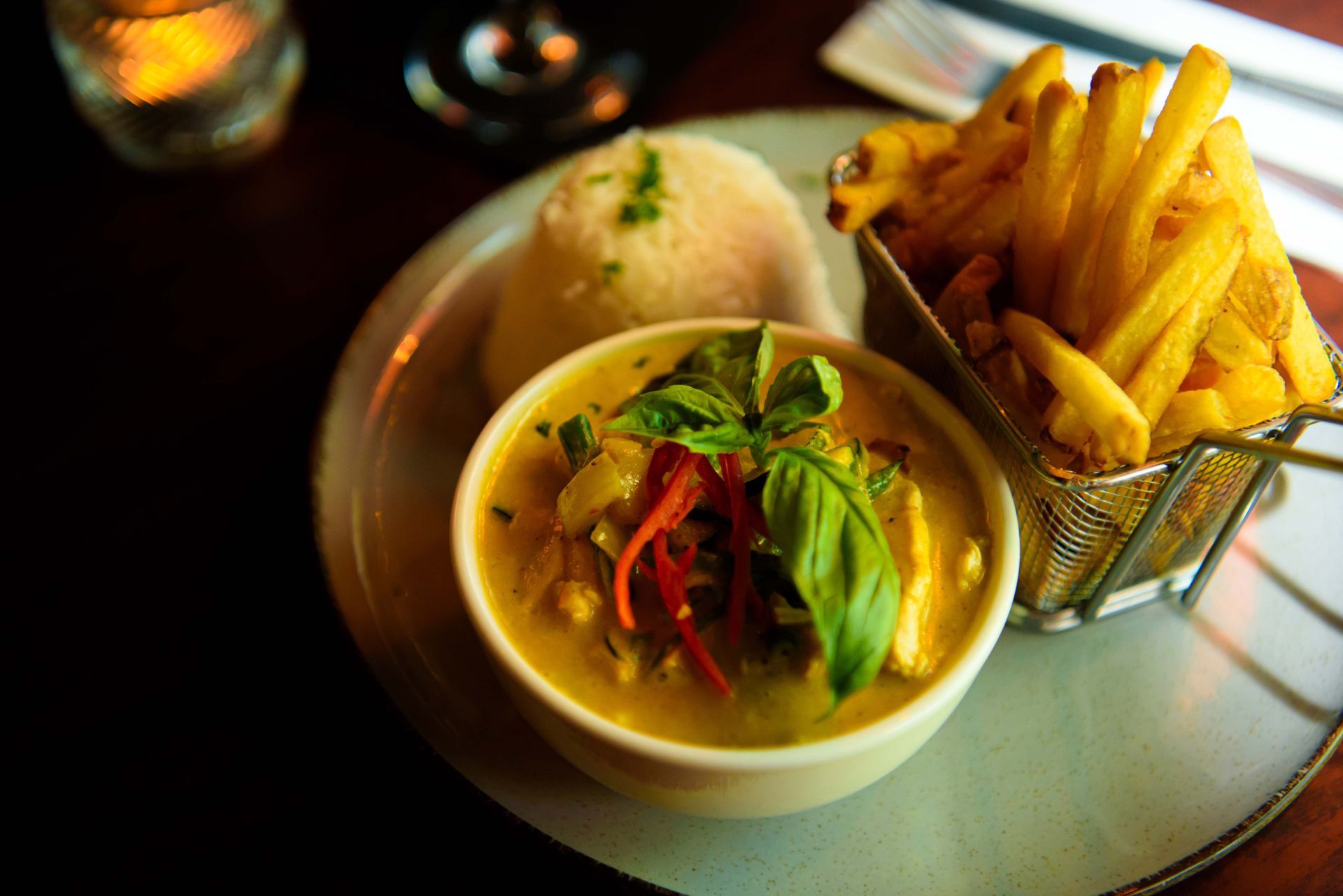 Yellow curry with rice and fries on a plate.