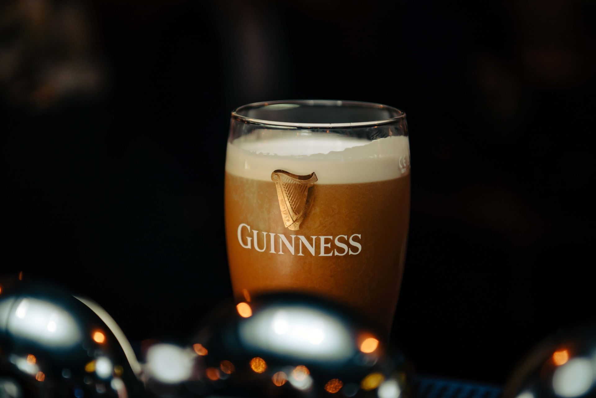 A pint of Guinness stout, creamy white head, in a branded glass, on a bar.