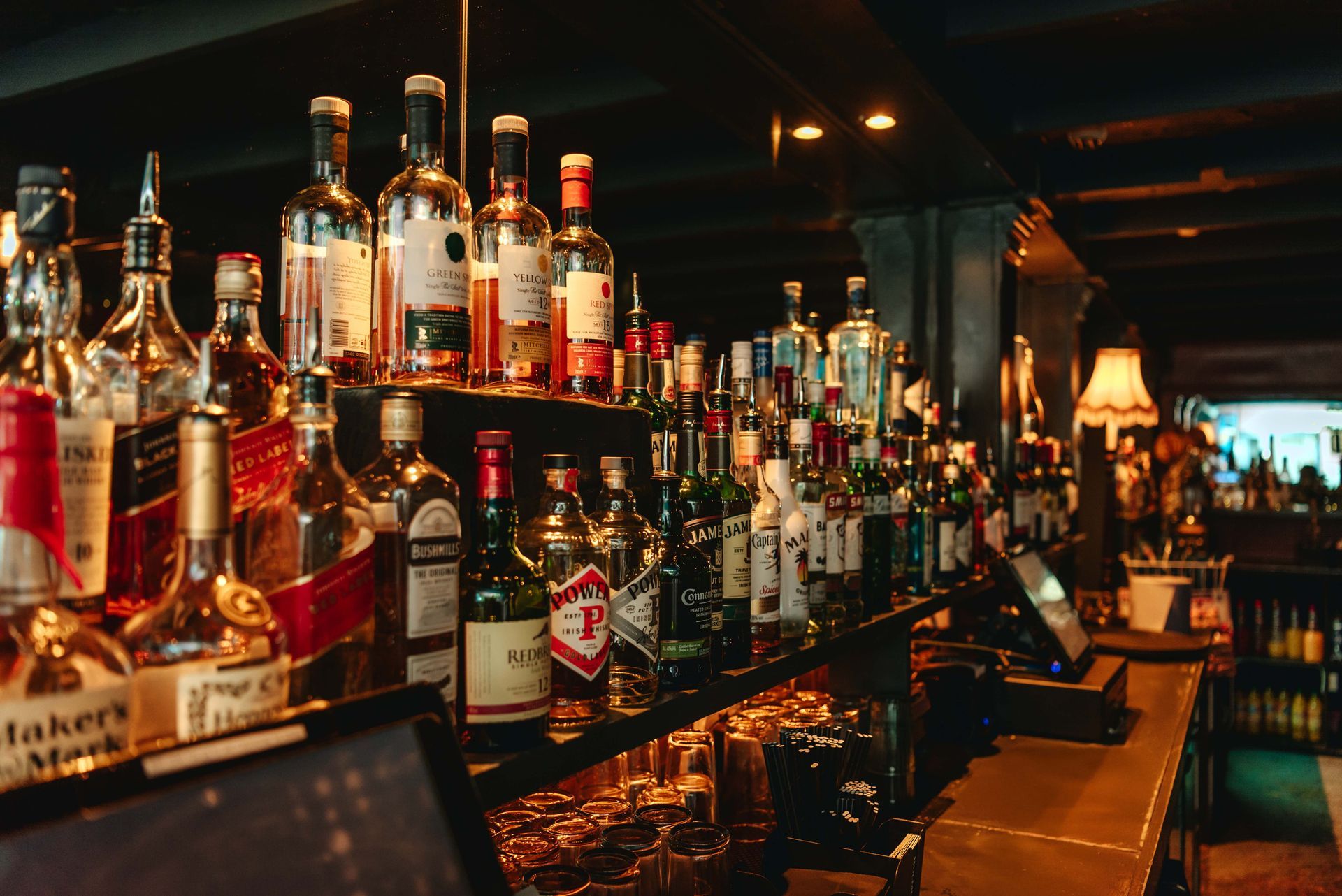 Bar with many liquor bottles on shelves, dim lighting.