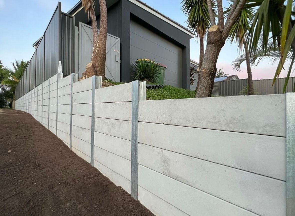 A brick wall with a green fence behind it.