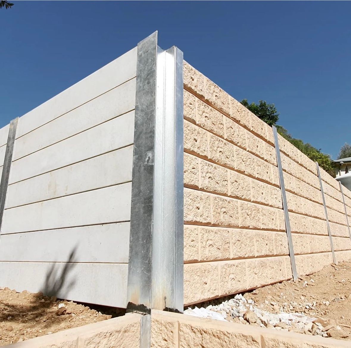 A brick wall is sitting on top of a dirt hill surrounded by trees.
