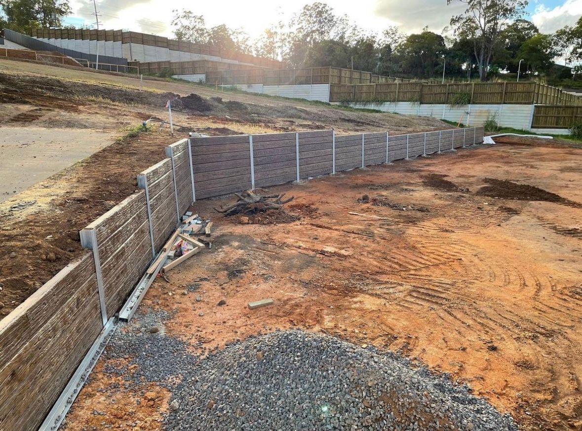 A concrete fence surrounds a house with trees in front of it.