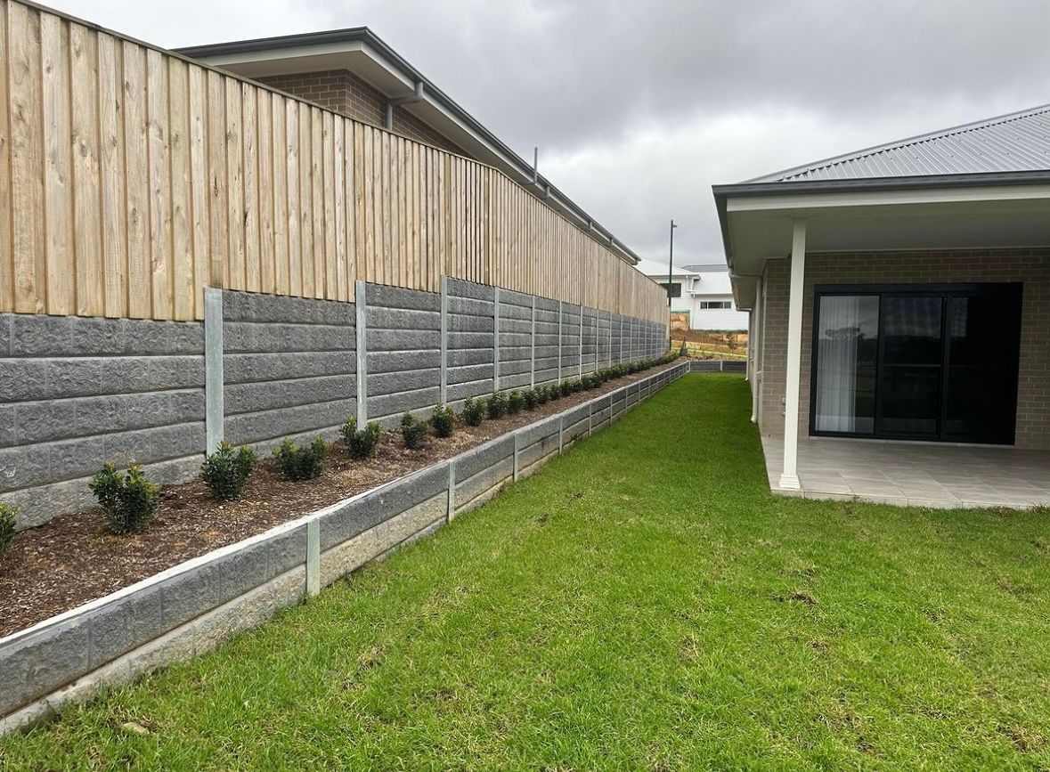 A house with a wooden fence and a large lawn in front of it.