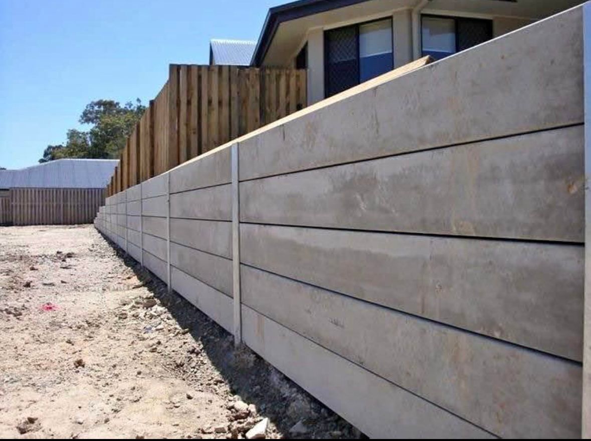 A concrete retaining wall is being built in front of a house.