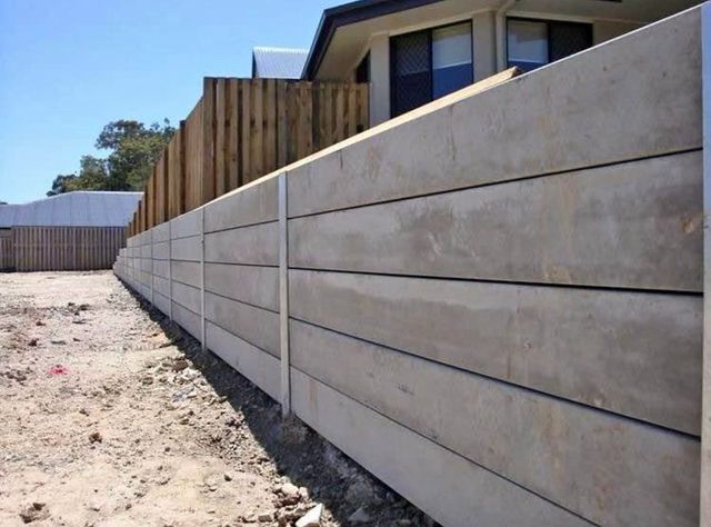 A concrete retaining wall is being built in front of a house.