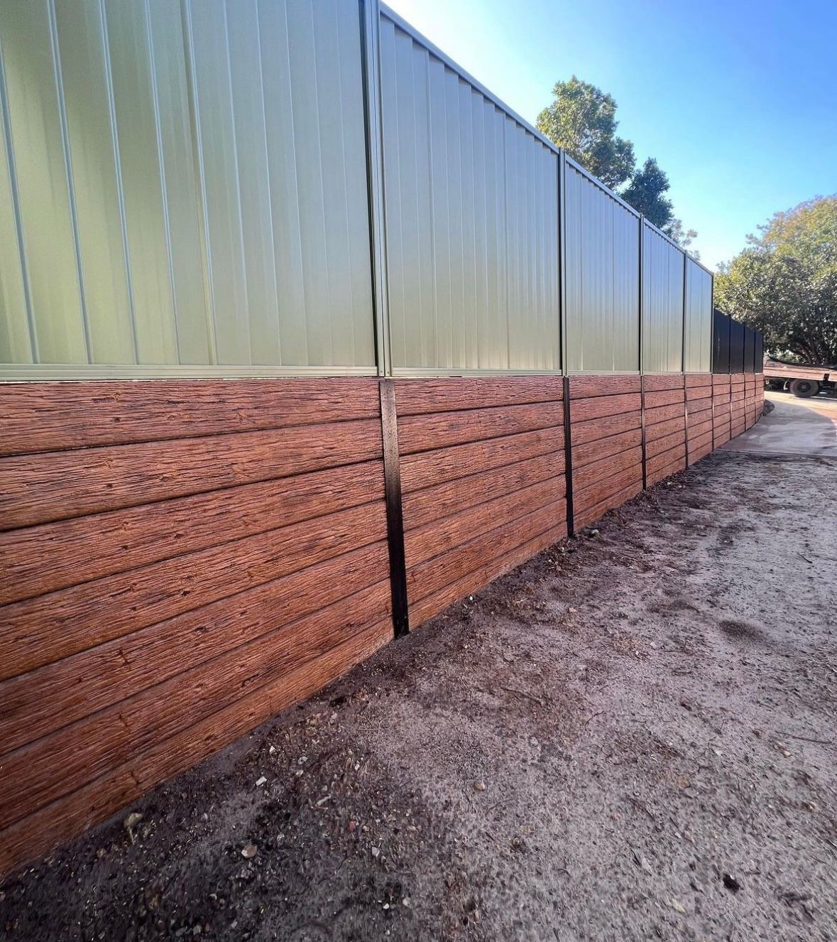 A wooden wall with a green fence behind it.