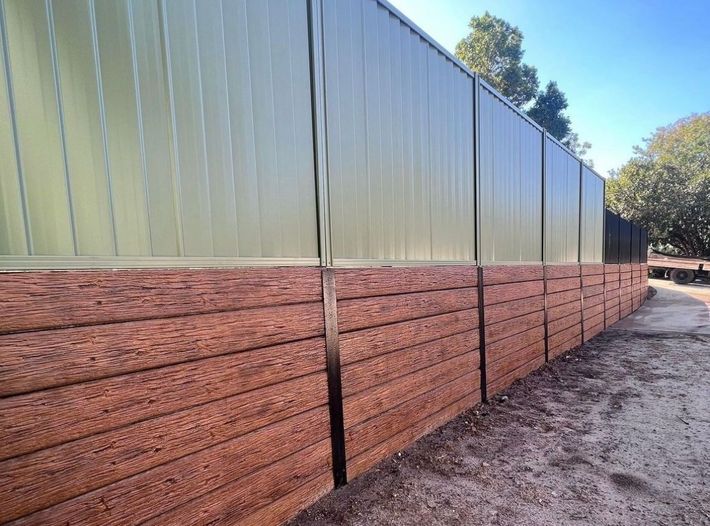 A wooden wall with a green fence behind it.