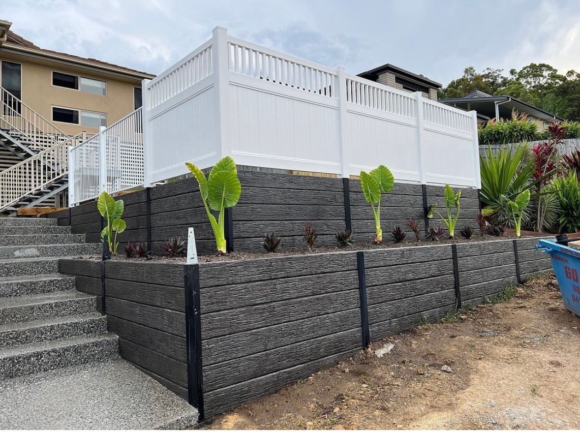 A white fence is sitting on top of a stone wall.