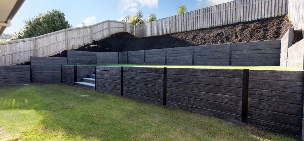 A large stone wall with stairs leading up to it in a backyard.
