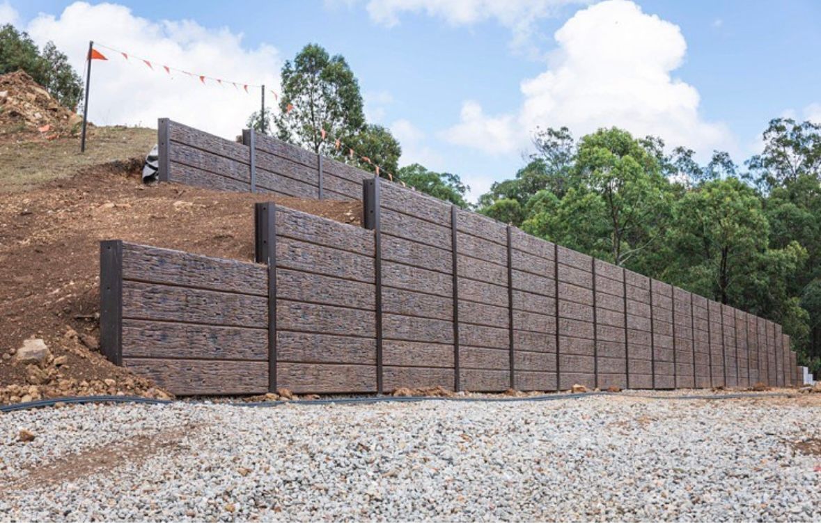 A large brick wall is being built on top of a gravel hill.