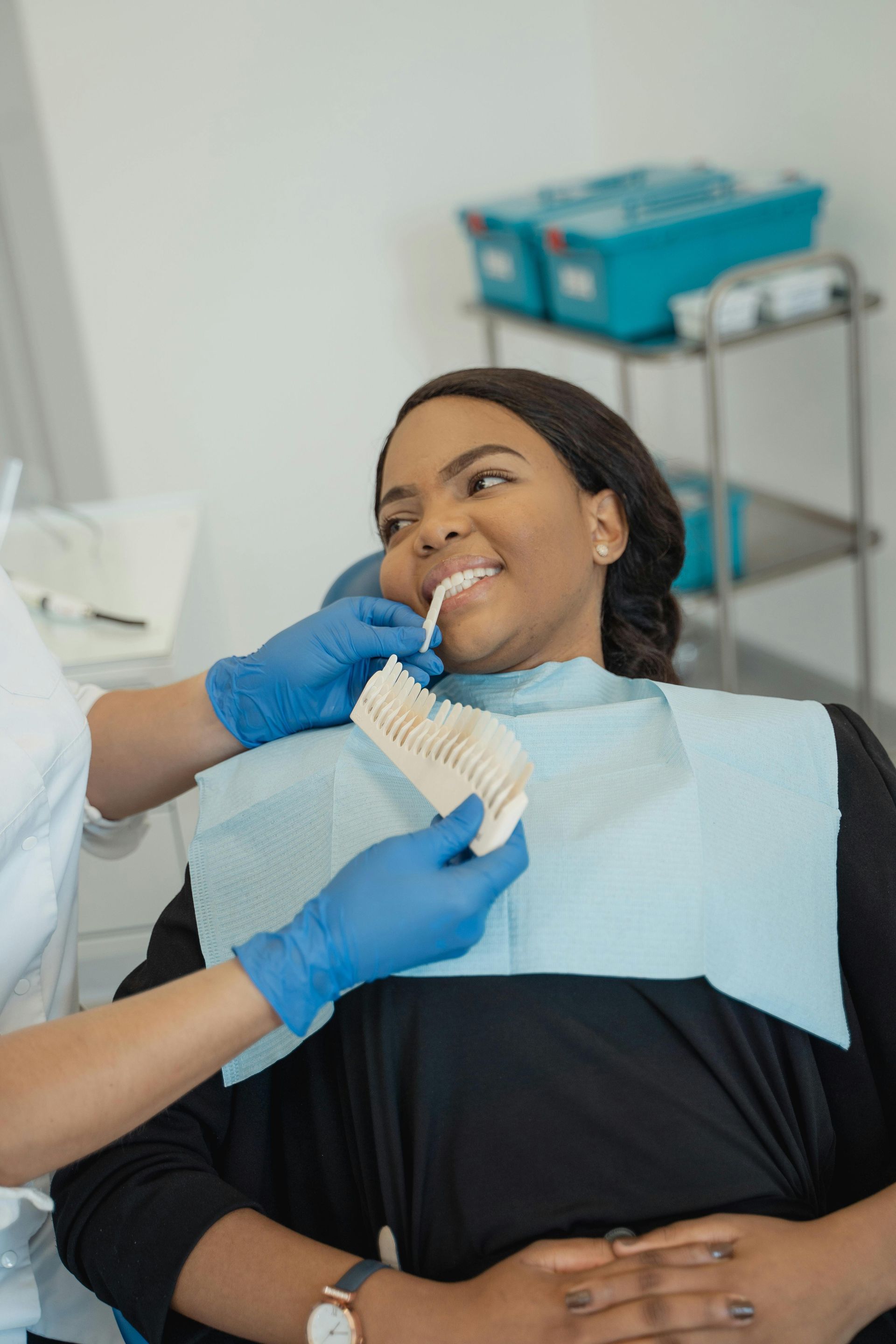 A woman is sitting in a dental chair getting her teeth examined by a dentist.