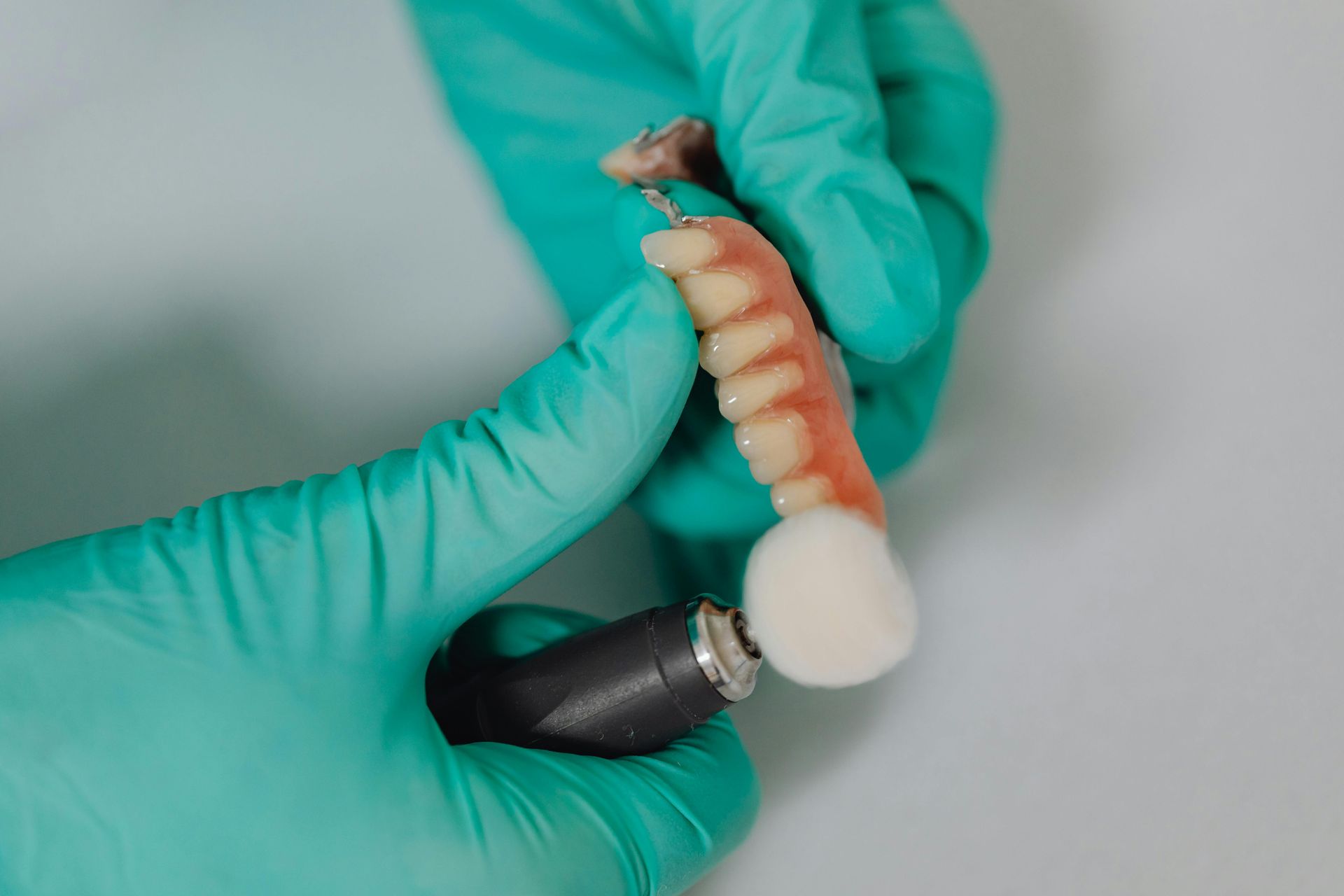 A dentist is polishing a denture with a brush.