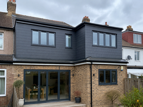 Modern two-story brick house with dark gray upper siding and a glass rear patio door