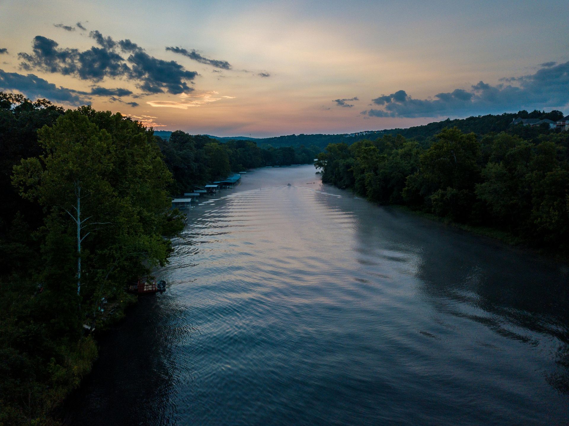 Calm river surrounded by trees at sunset