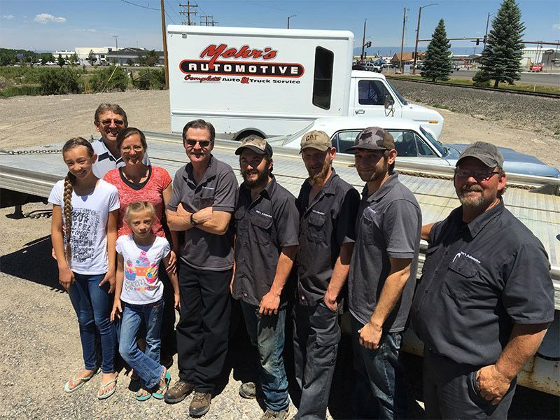 Group of people posing in front of a white truck;