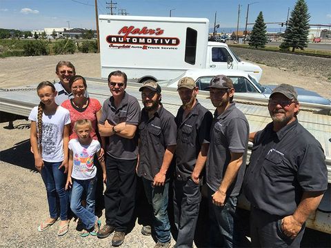 Group of people posing in front of a white truck; 