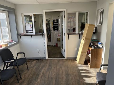 Waiting room with gray walls, dark wood floor, chairs, counter windows, and open doorway. | Mohr's Automotive