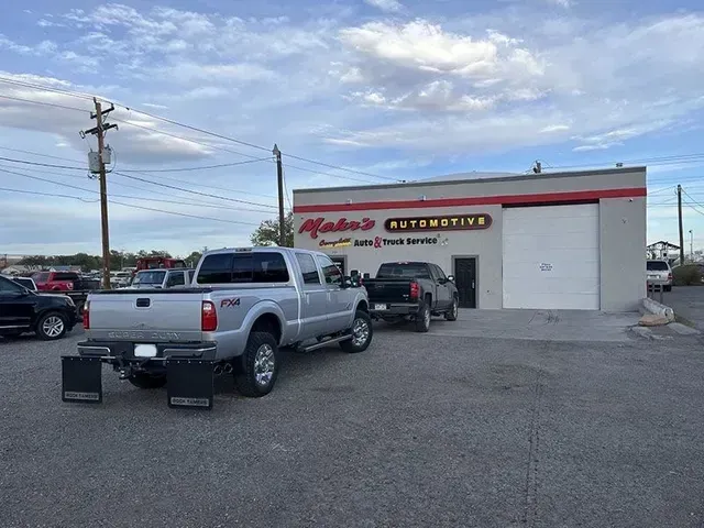 Silver pickup truck parked in front of Mako's Automotive shop with trucks and a cloudy sky. | Mohr's Automotive