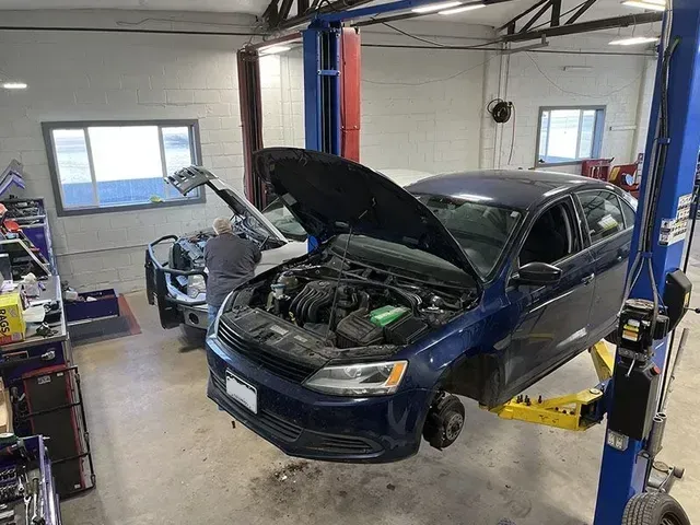 Car being repaired on a lift inside a repair shop, mechanic working under the hood. | Mohr's Automotive