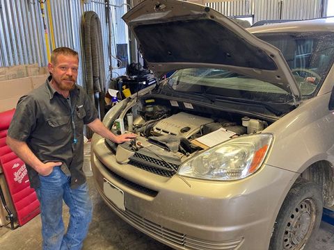 Mechanic standing next to a car with an open hood in a garage. | Mohr's Automotive