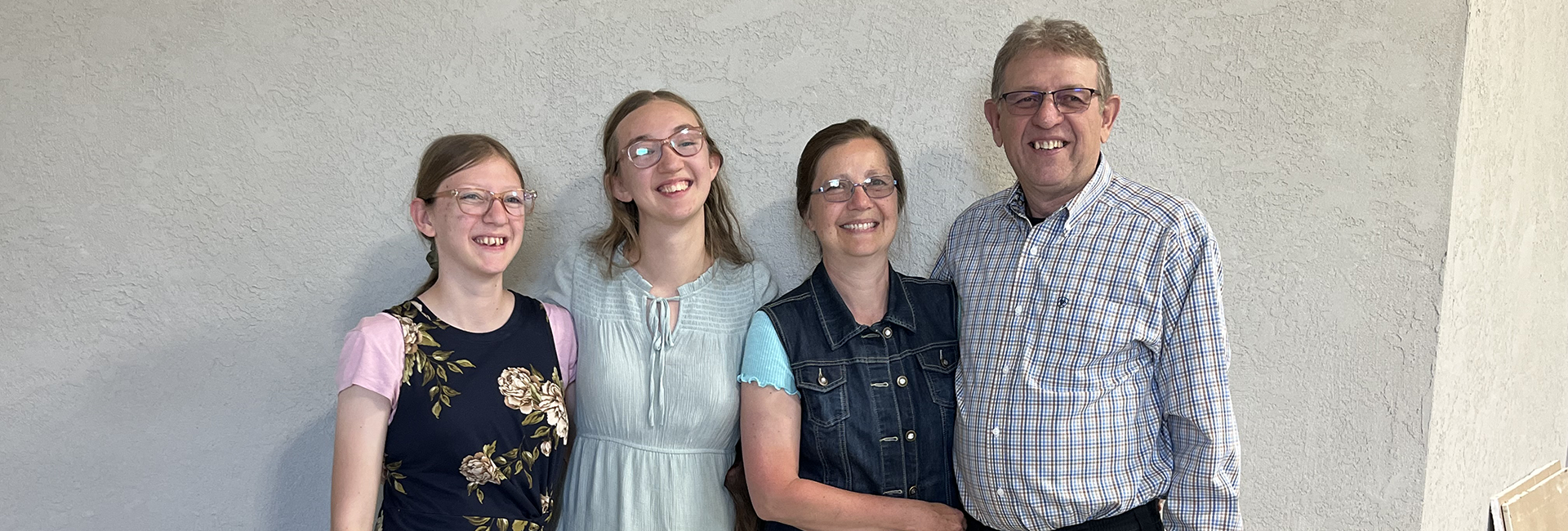 Four people smiling, posing in front of a gray wall. | Mohr's Automotive