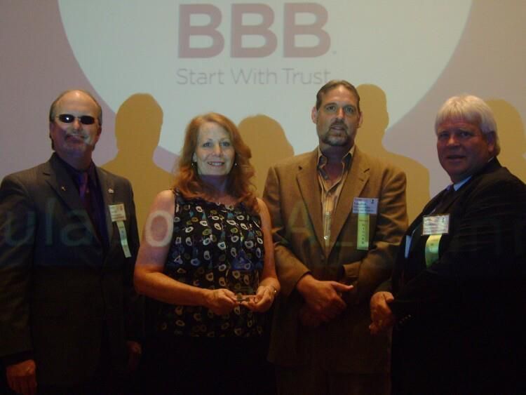 Four people stand in front of a BBB logo with 