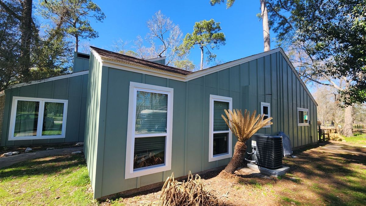 Green house with white-trimmed windows; palm tree in the front yard.