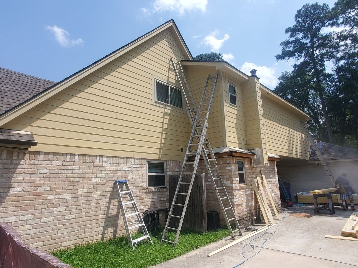 House exterior with ladders propped against the siding; construction in progress; sunny day.